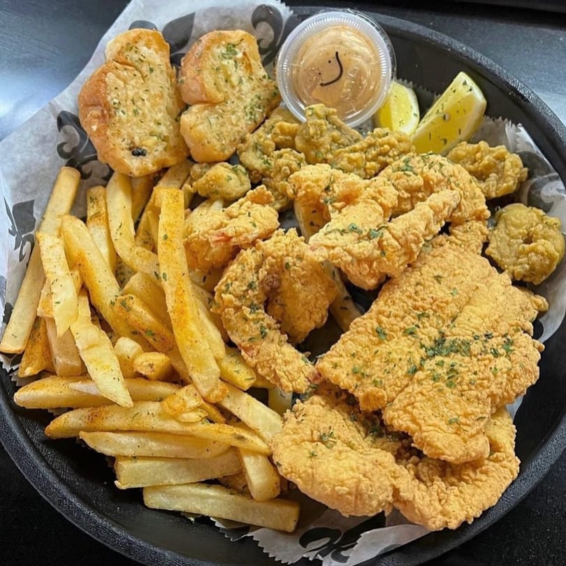 A platter of Smiley's Grill fried seafood, fries, garlic bread, and dipping sauce.